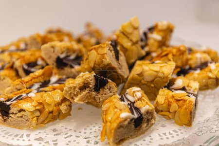 Photo horizontale une tentante gamme de pâtisseries arabes surmontées d'amandes effilées et d'une bruine de chocolat, présentée sur un délicat papier de dentelle. Concept alimentaire et culturel.