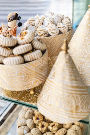 Vertikale fotokünstlerische Präsentation arabischer Süßigkeiten mit Schwerpunkt auf Maamoul in einem eleganten Rahmen, der kulinarische Tradition mit opulentem Design verbindet. Ernährungs- und Kulturkonzept.