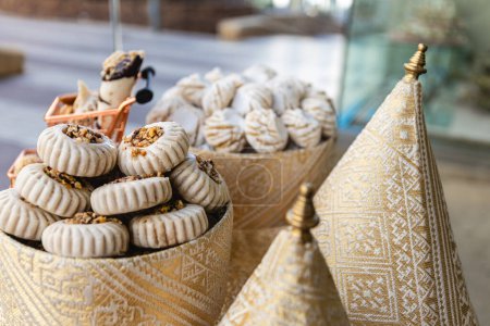 Horizontal photo a selective focus shot captures the intricate detail of artisanal Arabic pastries arrayed on a stand wrapped in traditional patterned fabric. Food and culture concept.