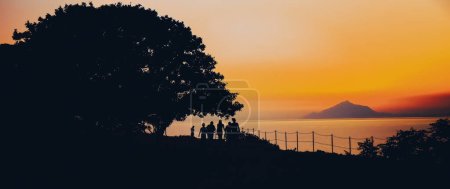 Téléchargez les photos : Coucher de soleil sur la mer Égée Lemnos ou Limnos île de Grèce idéal pour des vacances d'été avec des personnes silhouette. - en image libre de droit