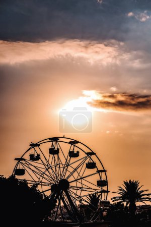 Foto de Silueta de la rueda de la fortuna en un cielo nublado y colores del atardecer, paseo de la diversión del verano. - Imagen libre de derechos