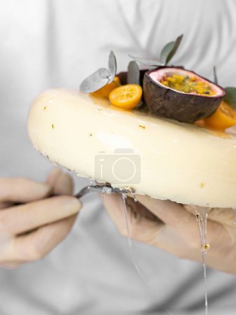 Photo for Female chef decorating with fresh passion fruit, delicious mousse cake - Royalty Free Image