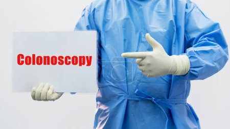Doctor or surgeon in blue gown holding clipboard or paper chart.Colonoscopy screening for cancer of colon.Surgeon pointing at colonoscopy label clipboard.Medical health promotion and prevention.