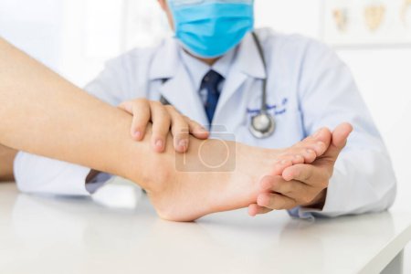 Photo for The orthopedic doctor or surgeon in white gown examined the patient with foot pain problem.White clean table or bed with blur background.Hallux or bunion with transfer metatarsalgia.Orthopaedic unit. - Royalty Free Image