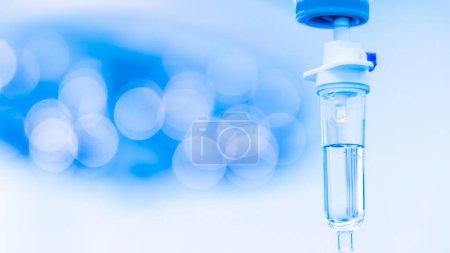 Blue tone of syringe pump with blurred background.Intravenous fluid used in the operating room while doctor did surgery.Surgical lamp in background.Medical concept.Emergency and shock patient.
