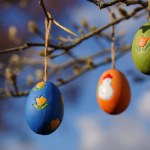 Colorful easter eggs hanging on tree branches on a sunny day with blue sky background. Concept of Easter in Germany. Frohe ostern.