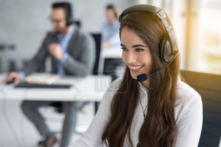 Foto de Closeup portrait of attractive young female customer support operator with headset working in call center - Imagen libre de derechos
