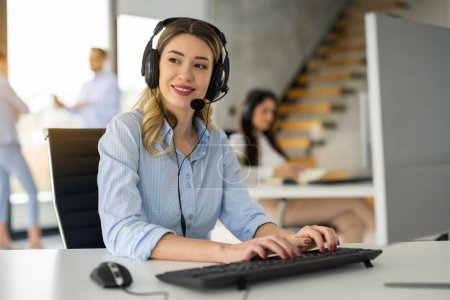 Photo for Beautiful customer support representative woman using computer in customer service office - Royalty Free Image