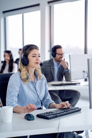 Photo for Attentive woman technical support agent listening to client with colleagues in customer service office, delivering top-notch customer service - Royalty Free Image