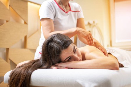 Téléchargez les photos : Jeune femme détendue profitant d'un massage complet du corps au salon de beauté spa. - en image libre de droit