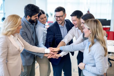 Photo for Group of businesspeople stacking hands in a tight circle, to strategize, motivate or celebrate their unity in the office. - Royalty Free Image
