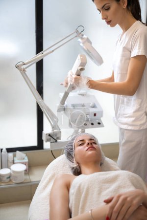 Beautiful woman having ozone therapy with facial steamer in beauty salon
