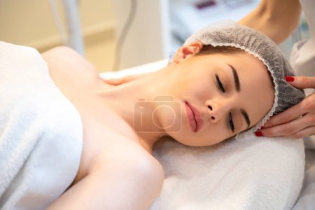 Close up portrait of beautiful woman receiving facial massage at luxury spa