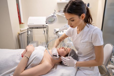 Foto de Esteticista realizando un procedimiento de rejuvenecimiento a una mujer joven en una clínica de belleza. - Imagen libre de derechos