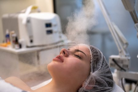 Photo for Close up of beautiful woman during ozone facial steamer face treatment in beauty clinic - Royalty Free Image