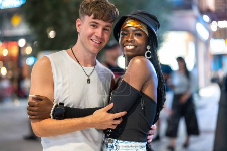 Téléchargez les photos : Portrait de jeune couple heureux amoureux posant ensemble dans la rue la nuit - en image libre de droit