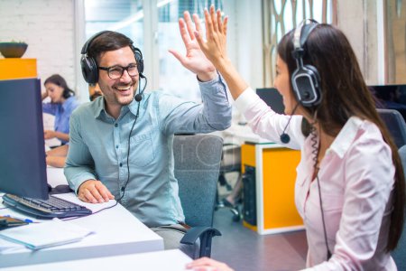 Photo for Customer support representative operators giving high five to each other celebrating successful task done at office. - Royalty Free Image