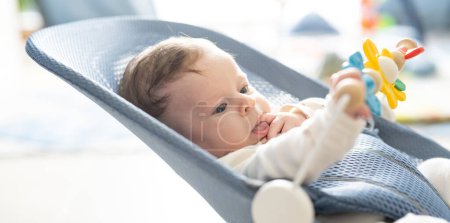 Téléchargez les photos : Mignon bébé souriant posé dans une chaise de videur. Enfant jouant dans une balançoire. - en image libre de droit