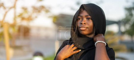 Foto de Retrato de una hermosa mujer africana con vestido negro Abaya al aire libre - Imagen libre de derechos