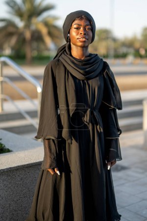 Photo for Portrait of beautiful muslim woman wearing traditional Abaya dress on city street at sunset - Royalty Free Image