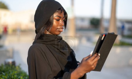 Photo for Portrait of beautiful young African woman using tablet outdoors - Royalty Free Image