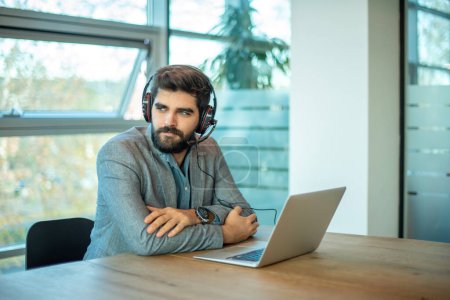 Téléchargez les photos : Jeune homme d'affaires réfléchi et beau qui travaille sur ordinateur au bureau - en image libre de droit