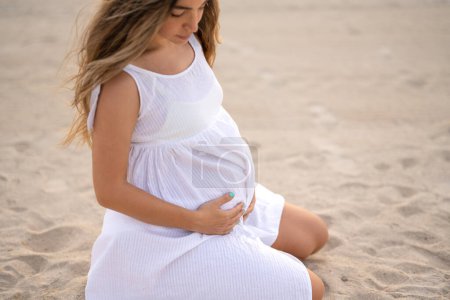 Foto de Por encima de la vista de la mujer embarazada sosteniendo su estómago. Expectativas del bebé y concepto de embarazo. Enfócate en las manos y el vientre de las mujeres - Imagen libre de derechos