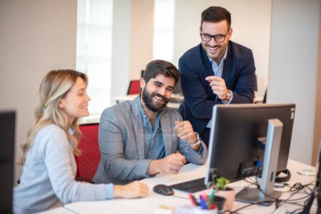 Foto de Grupo de tres personas de negocios riendo juntas mientras miran el monitor de la computadora y obtienen buenos resultados de la compañía - Imagen libre de derechos