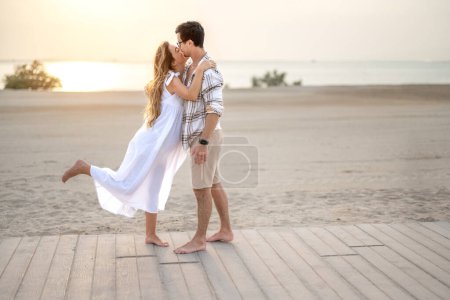 Photo for Romantic scene of beautiful young pregnant couple embraced on the beach at sunset - Royalty Free Image