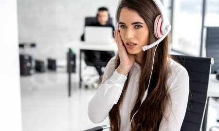 Téléchargez les photos : Dérangé opérateur de soutien féminin écoute attentivement le client tout en parlant sur casque dans le centre d'appels - en image libre de droit