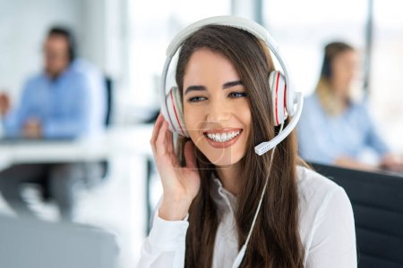 Photo for Portrait of smiling female support agent with headset working on computer at call center office - Royalty Free Image