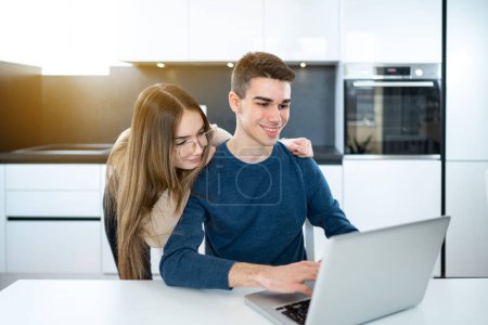Téléchargez les photos : Jeune couple d'adolescents utilisant un ordinateur portable ensemble à la maison - en image libre de droit