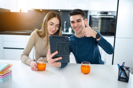 Téléchargez les photos : Jeune couple parlant avec la famille sur appel vidéo et montrant pouces vers le haut - en image libre de droit