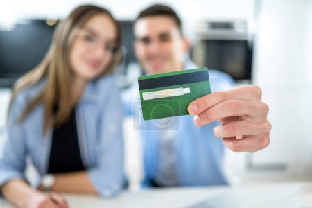 Photo for Close up of male hand holding credit card. Happy young couple enjoying making purchases online, shopping and using banking services. - Royalty Free Image