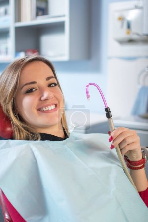 Young female patient smiling and holding suction tube.