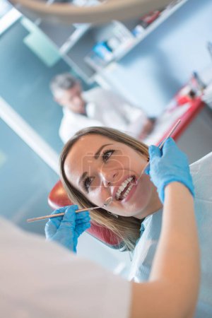 Téléchargez les photos : Dentiste examinant un patient dents dans le cabinet dentaire. - en image libre de droit