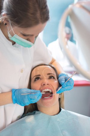 Téléchargez les photos : Dentiste examinant un patient dents dans le cabinet dentaire. - en image libre de droit