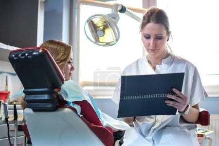 Téléchargez les photos : Dentiste tenant un calendrier et organisant un horaire pour la prochaine visite du patient. - en image libre de droit