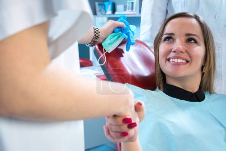 Foto de Primer plano de la paciente mujer estrechando la mano con el dentista en el consultorio de dentistas. - Imagen libre de derechos