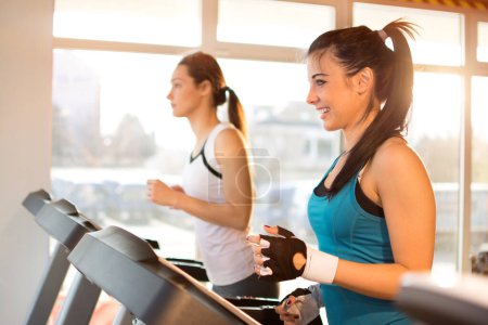 Photo for Pretty smiling girl working out in a treadmill at the gym. - Royalty Free Image