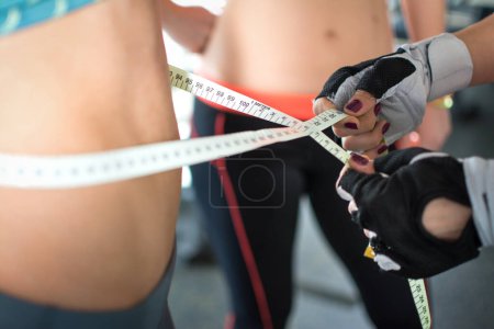 Téléchargez les photos : Copines sportives se mesurant avec un ruban à mesurer, gros plan. - en image libre de droit
