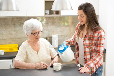 Téléchargez les photos : Petite-fille apportant une tasse de thé à sa grand-mère. - en image libre de droit
