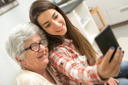 Seniorin macht Selfie mit ihrer kleinen Enkelin zu Hause.