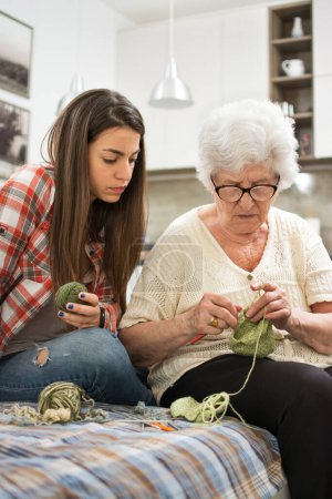 Téléchargez les photos : Grand-mère montrant à sa petite-fille comment tricoter
. - en image libre de droit