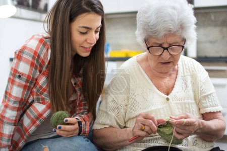 Téléchargez les photos : Petite-fille apprendre à tricoter de sa grand-mère. - en image libre de droit