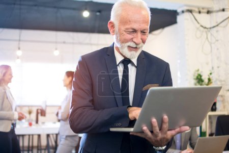 Téléchargez les photos : Portrait d'un homme d'affaires expérimenté utilisant un ordinateur portable alors qu'il était au bureau - en image libre de droit