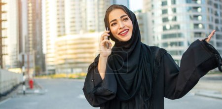 Foto de Hermosa mujer árabe hablando por teléfono en la calle con ropa árabe tradicional - Imagen libre de derechos