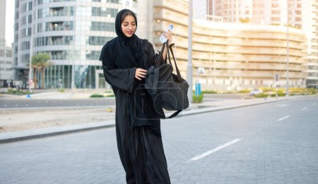 Photo for Beautiful muslim woman with water bottle and sports bag going to the gym - Royalty Free Image
