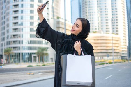 Photo for Young beautiful Arabian middle eastern woman taking selfie with mobile phone on the city street - Royalty Free Image