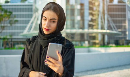 Téléchargez les photos : Jeune belle Arabe Moyen-Orient femme prendre selfie avec téléphone portable sur la rue de la ville - en image libre de droit